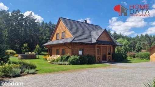 Dom zatopiony w zieleni, z furtką do lasu.