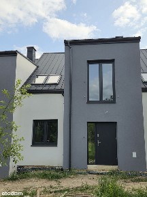 Domy w zabudowie szeregowej otoczone zielenią.