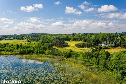 Dom nad jeziorem z linią brzegową, pomostem i parkiem